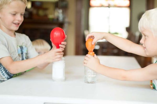 two children blowing balloons with vinegar and baking soda