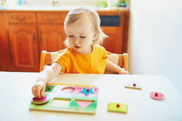 Toddler playing with wooden puzzle.