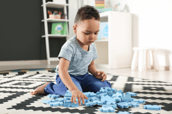 Child playing with blue puzzle pieces on the floor