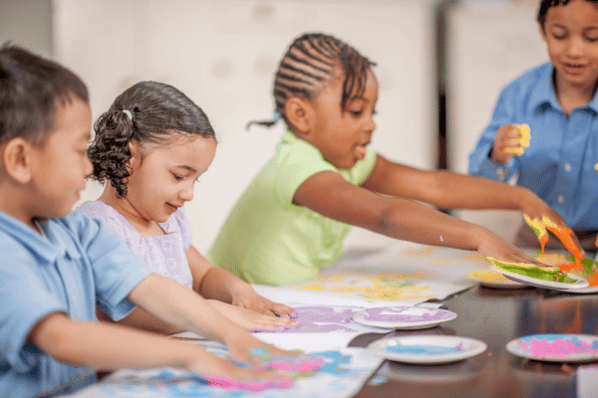 Children fingerpainting in art class in preschool.