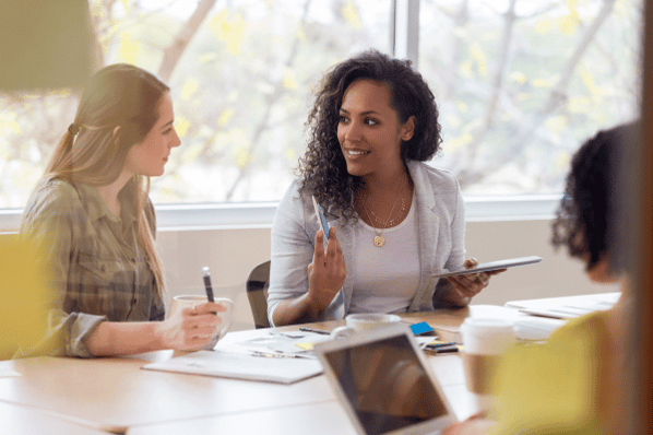 Two women talking at staff meeting