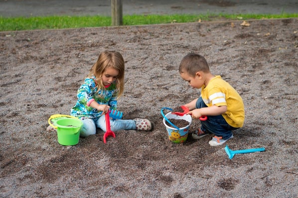 two children playing with toys in a sandbox
