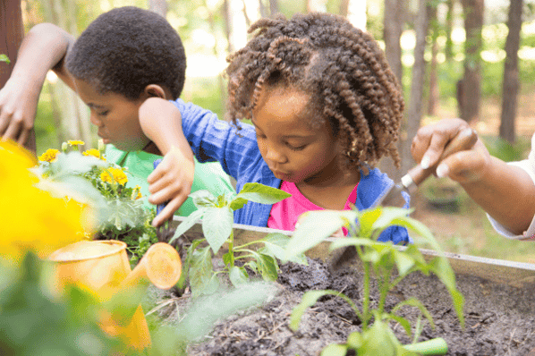 Two young children gardening outdoors in spring at preschool.