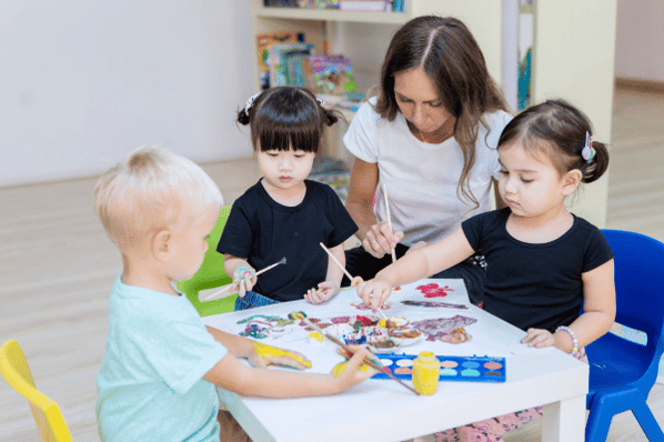 Children painting with teacher at daycare.