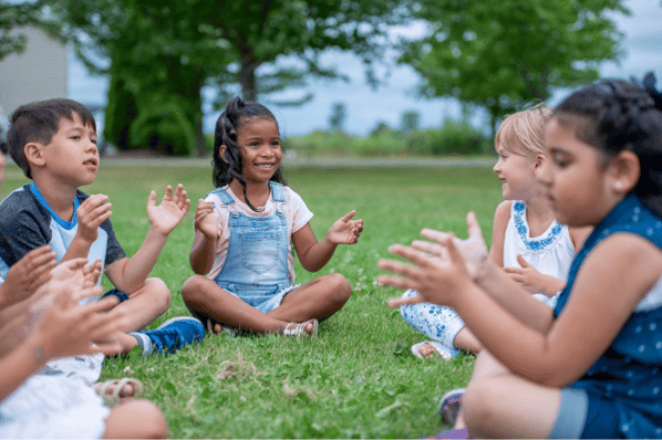 literacy circle time activities Preschool circle sitting in a circle outside, clapping their hands.