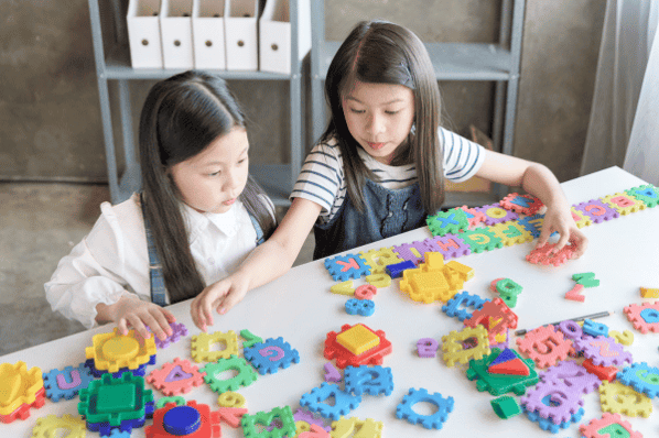 Two girls playing with letter puzzle.