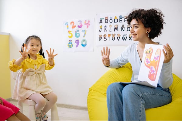 imageYoung girl counting to four with her teacher