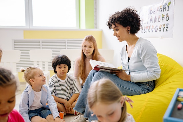 woman reading book to children