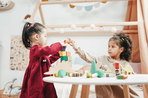 two little girls playing with blocks at table