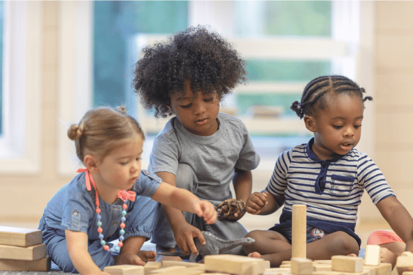 three preschool children playing with wooden blocks