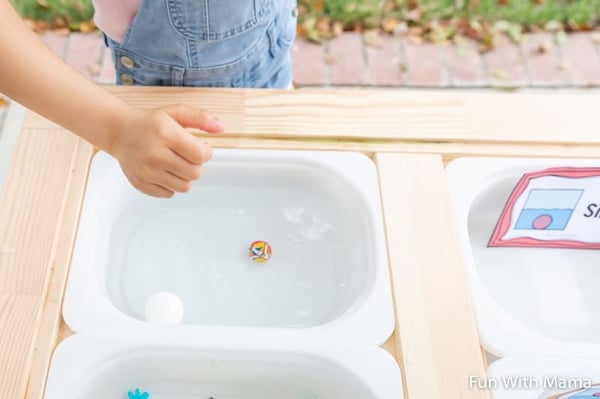 a child trying to sink and float objects at a water table