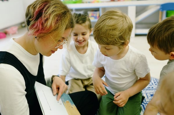 Teacher reading to three children at preschool