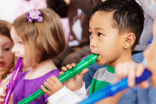 Two preschool children playing plastic flutes. 
