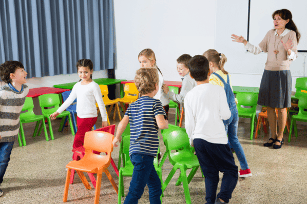 Children and teacher playing musical chairs.