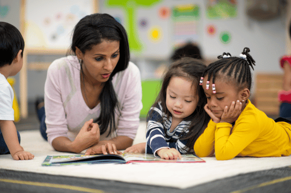Preschool teacher reading with two children.