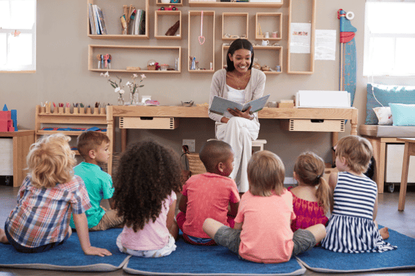 Preschool teacher in Montessori classroom reading to a group of children