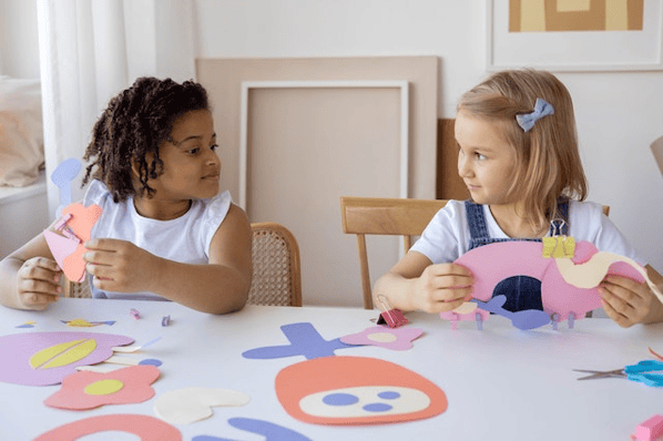 Two young girls doing arts and crafts at a table
