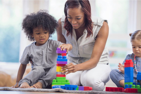 Teacher helping toddler stack colorful legos