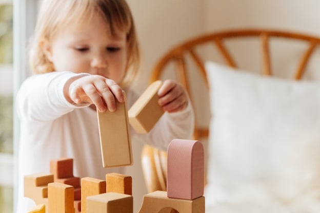 little girl playing with wooden blocks in a montessori classroom
