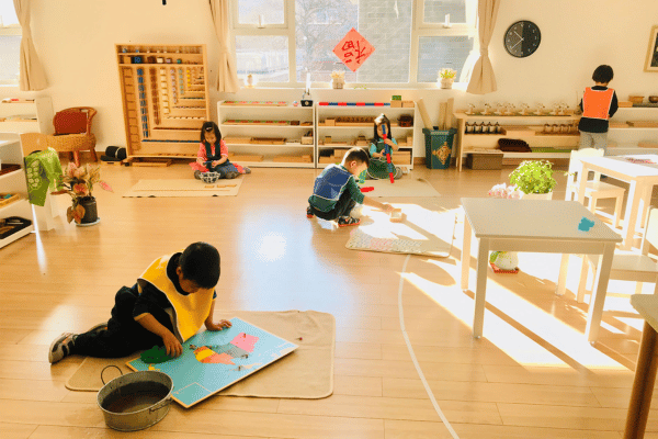 children learning in separate areas in a montessori classroom