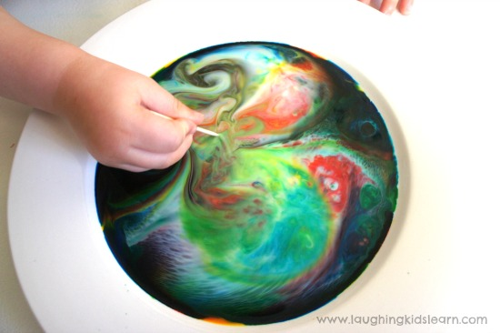 a child mixing milk and food colors in a plate 