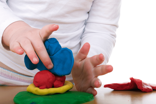 child playing with blue, red, yellow, and green play dough